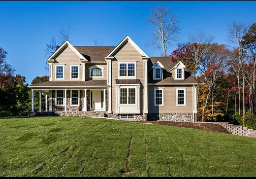 Tan colonial home surrounded by fall foliage — Storybook Homes NJ