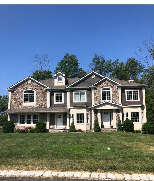 Dark stone-and-siding colonial with dramatic mature trees — Storybook Homes NJ
