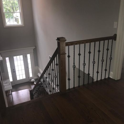 Staircase with wrought iron railing overlooking the foyer — Storybook Homes NJ