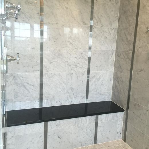 Primary bathroom shower with marble slab walls and built-in bench — Storybook Homes NJ