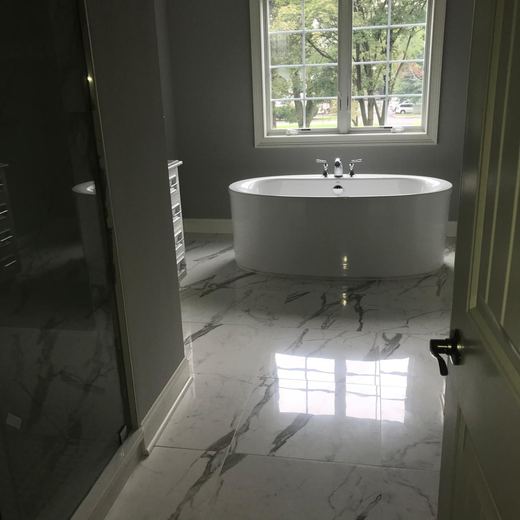 Primary bathroom with freestanding soaking tub beneath a picture window — Storybook Homes NJ