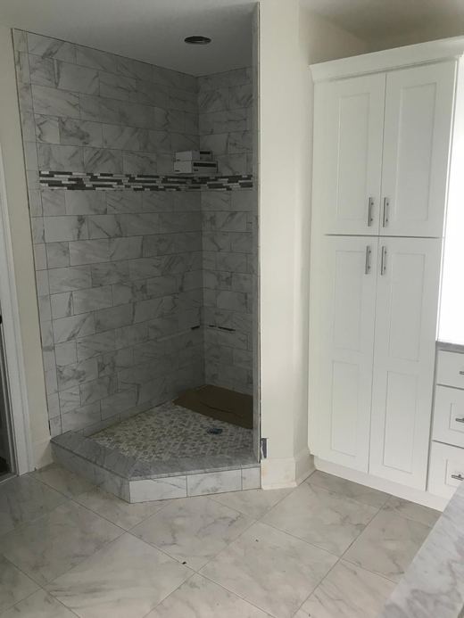 Primary bathroom shower with marble tile and mosaic accent shelf — Storybook Homes NJ