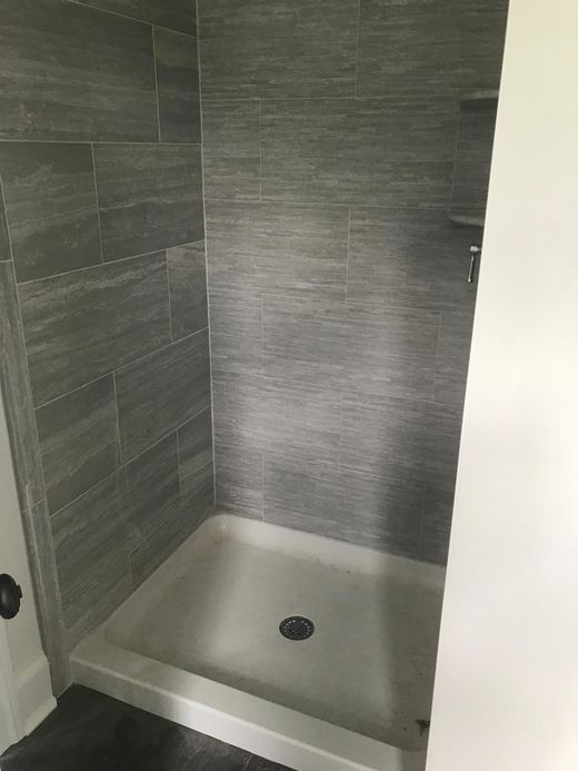 Primary bathroom shower with large-format gray tile — Storybook Homes NJ